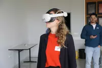 Reha Fachtagung 2025 Titelbild Eine Teilnehmerin der Reha-Fachtagung testet mithilfe einer Virtual-Reality-Brille digitale Lern- und Trainingsanwendungen. Neue Technologien wie VR eröffnen in der Rehabilitation innovative Wege für praxisnahe Übungen und anschauliche Schulungserlebnisse.