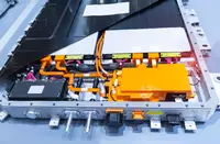 Geöffnete Hochvoltbatterie eines Elektrofahrzeugs mit sichtbaren Batteriemodulen, orangefarbenen Hochvoltleitungen, Steckverbindungen und Steuerungskomponenten.