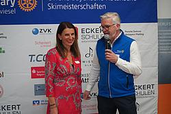 Ansprache Golsponsor: Andrea Radlbeck in Vertretung für das Berufsförderungswerk Eckert. Andrea Radlbeck steht in einem roten Kleid vor der Sponsorentafel und wird von einem Vertreter des Rotary Clubs interviewt.