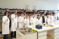 Boys Day 04 Gruppe von Schülern und Lehrkräften im Labor zeigt Daumen hoch.