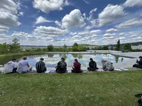 Kreativ Gruppe Sommersemester Studierende der Kreativ-Gruppe sitzen am Teich des Campus Regenstauf und arbeiten bei sonnigem Wetter an Zeichnungen und Projekten.