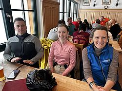 Mehrere Teilnehmende der Rotary Skimeisterschaft Indoor in der Hütte sitzen gesellig zusammen.