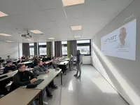 Carbon nein danke Fachvortrag zur Sektorenkopplung am Campus Regenstauf Ein Referent steht vorne in einem modernen Unterrichtsraum und hält einen Fachvortrag vor Vollzeit Studierenden der Weiterbildung zum Heizungs Sanitär und Klimatechniker. Die Teilnehmenden sitzen an Tischen und verfolgen aufmerksam die Präsentation zum Thema Sektorenkopplung und energieeffiziente Gebäudetechnik.