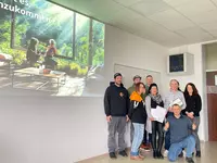 Teilnehmerinnen und Teilnehmer des Projekts „Leben.Raum“ stehen gemeinsam mit den betreuenden Lehrkräften vor einer projizierten Visualisierung eines Architekturmotivs.