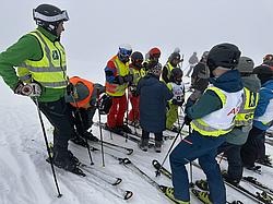 Mehrere Teilnehmende der Rotary Skimeisterschaft stehen startbereit auf der Piste. Unter den Teilnehmenden befinden sich sowohl Erwachsene als auch Kinder. Das Wetter ist auffällig neblig.