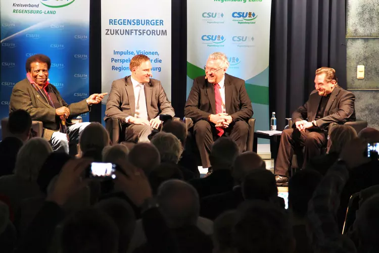 (V.l.n.r.) Entertainer Roberto Blanco, CSU-Kreisvorsitzender und Moderator der Abends Peter Aumer, Bayerns Innenminister Joachim Herrmann und der Caritasdirektor der Diözese Regensburg, Dr. Roland Batz diskutieren die aktuelle Flüchtlingssituation am Campus der Eckert Schulen in Regenstauf.